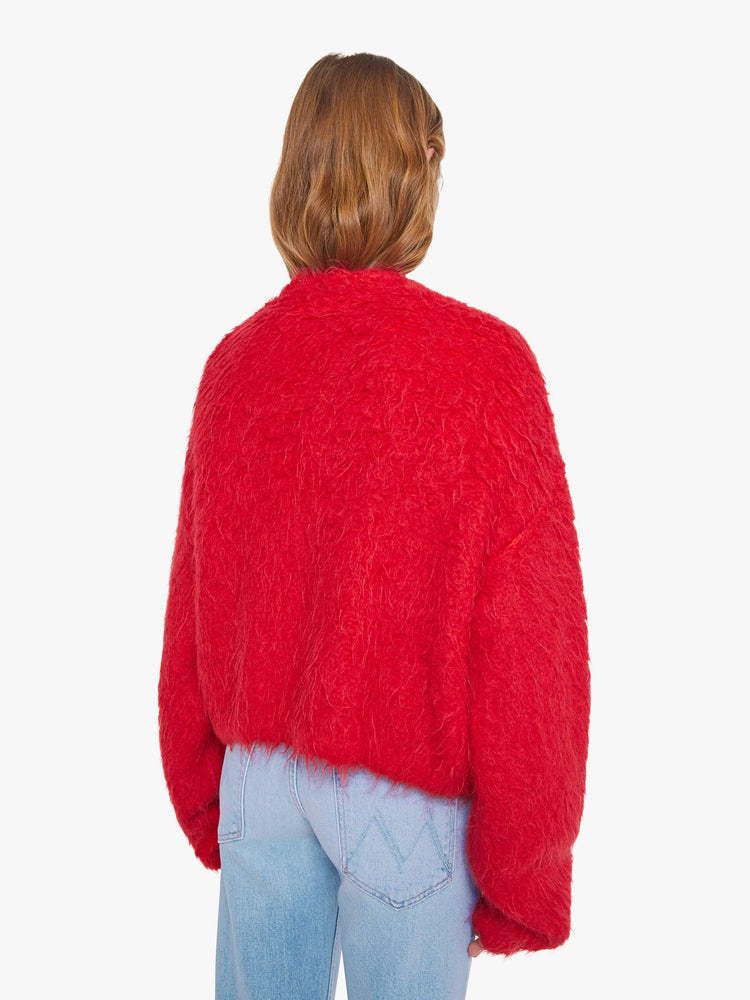 Back view of a woman in a red crewneck cardigan with drop shoulders, balloon sleeves and a slightly oversized fit. 