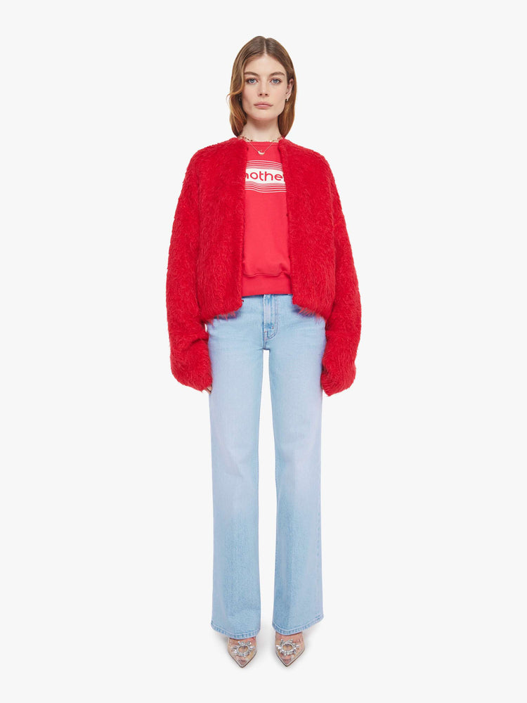 Full body view of a woman in a red crewneck cardigan with drop shoulders, balloon sleeves and a slightly oversized fit. 