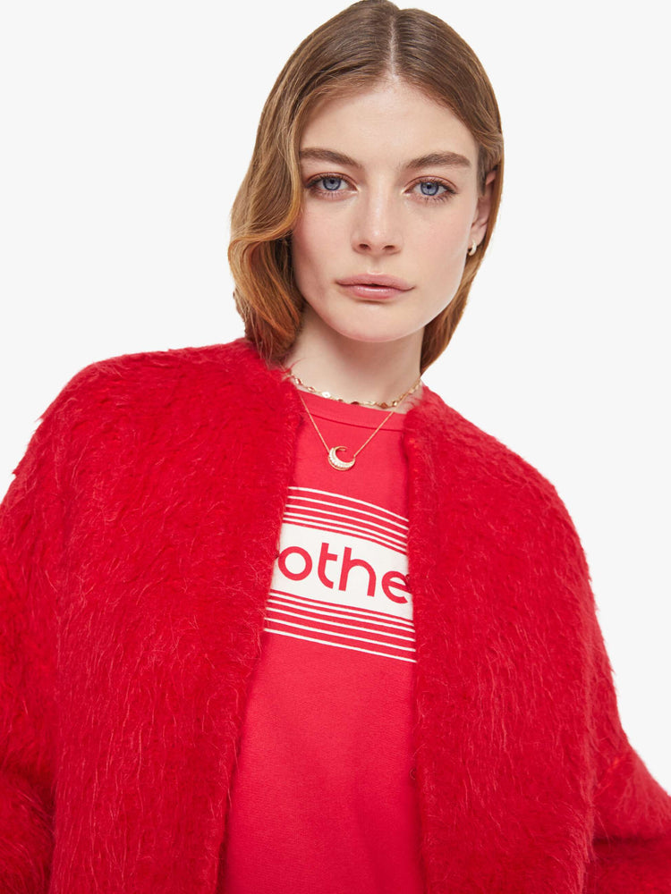 Close up view of a woman in a red crewneck cardigan with drop shoulders, balloon sleeves and a slightly oversized fit. 