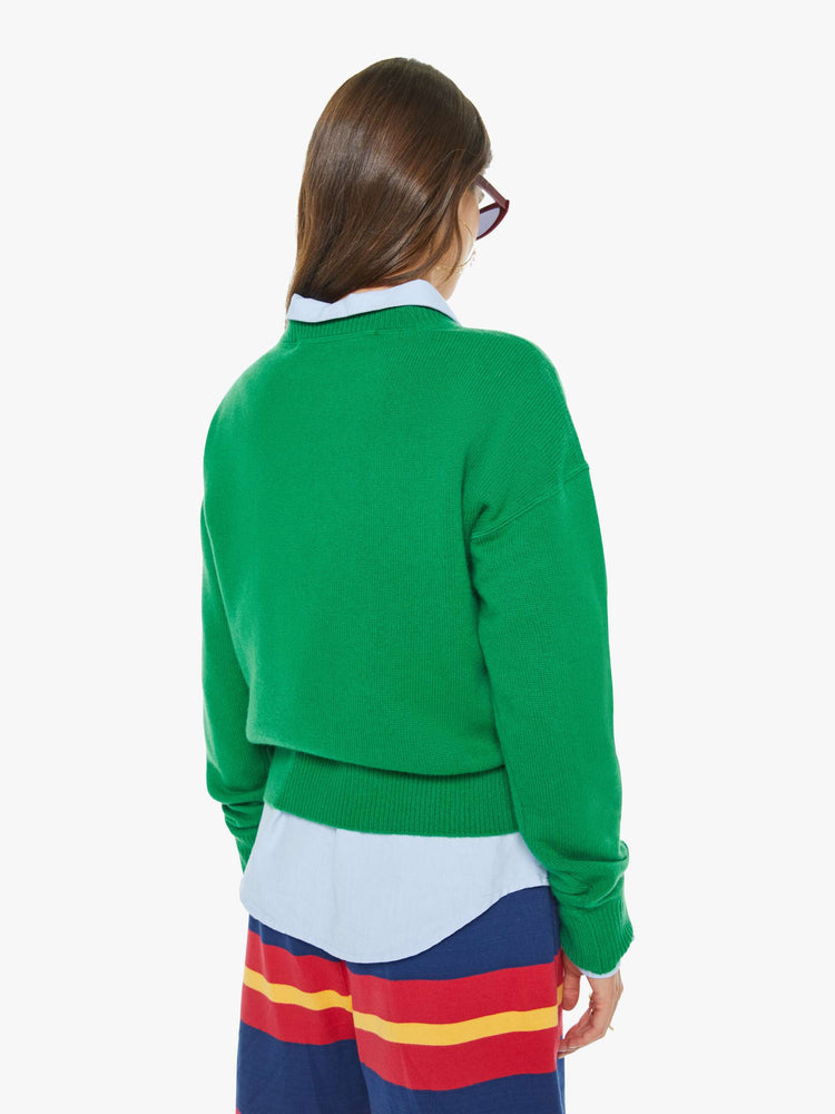 Back view of a woman in a green crewneck sweater with drop shoulders, ribbed hems and an oversized fit.