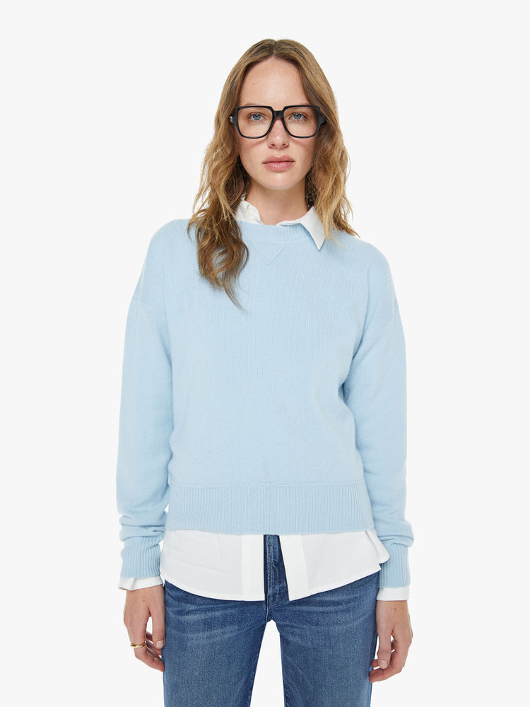 Front view of a woman in a light blue crewneck sweater with drop shoulders, ribbed hems and an oversized fit.