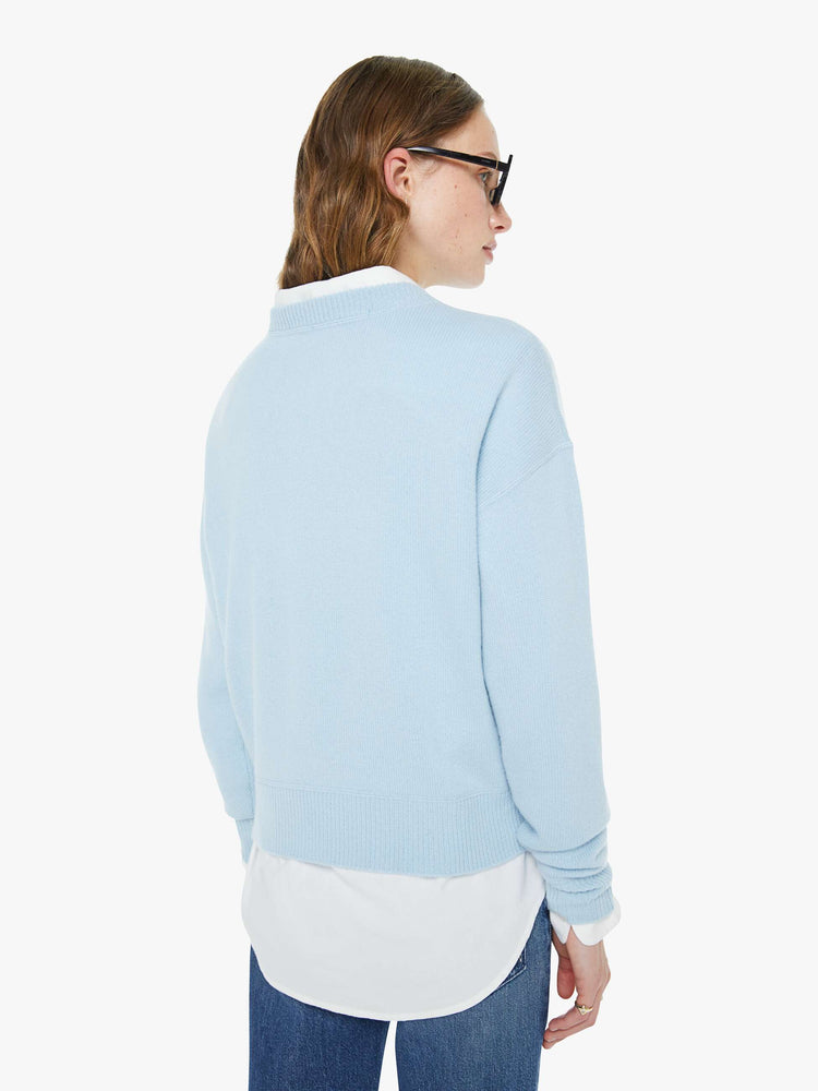 Back view of a woman in a light blue crewneck sweater with drop shoulders, ribbed hems and an oversized fit.