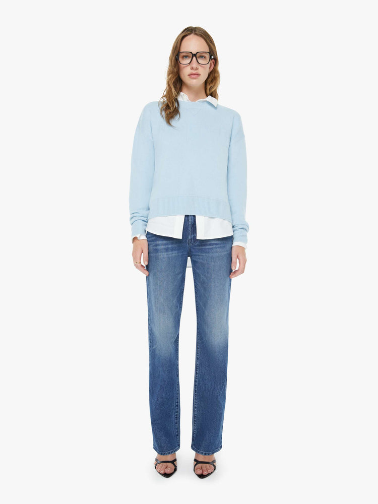 Full body view of a woman in a light blue crewneck sweater with drop shoulders, ribbed hems and an oversized fit.