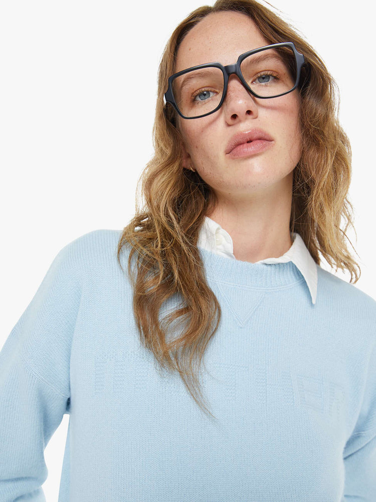 Close up view of a woman in a light blue crewneck sweater with drop shoulders, ribbed hems and an oversized fit.