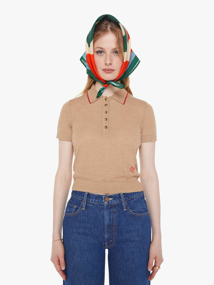 Front view of a woman in a light khaki with red details and trim knit polo shirt with short sleeves, a buttoned V-neck, ribbed hems and a slightly cropped fit.