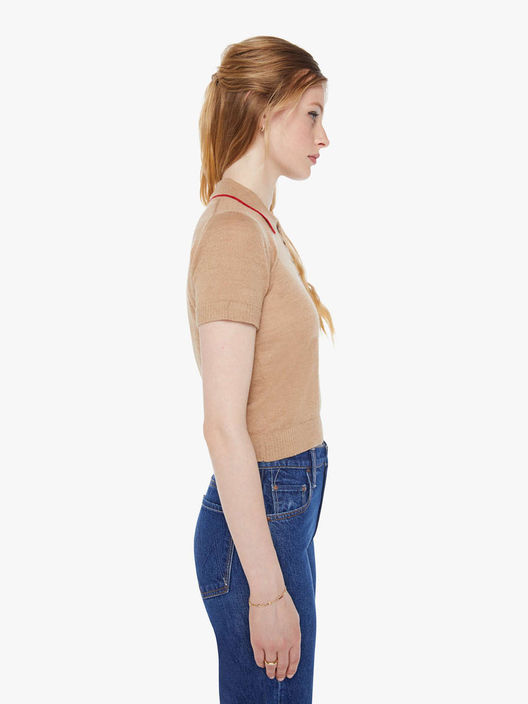 Side view of a woman in a light khaki with red details and trim knit polo shirt with short sleeves, a buttoned V-neck, ribbed hems and a slightly cropped fit.