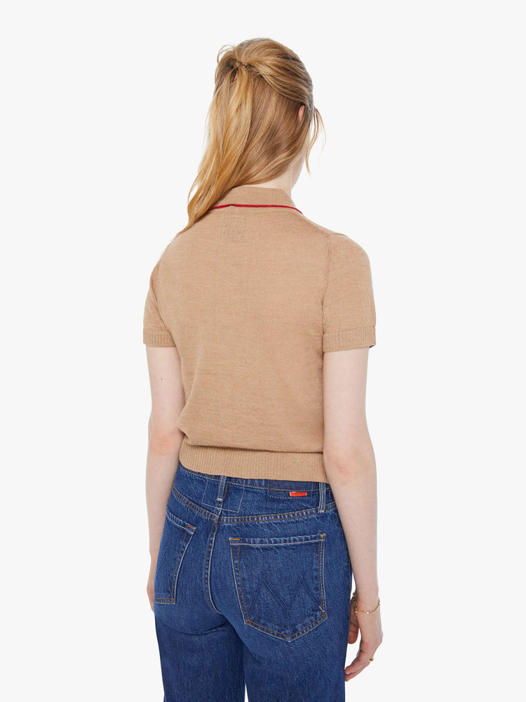 Back view of a woman in a light khaki with red details and trim knit polo shirt with short sleeves, a buttoned V-neck, ribbed hems and a slightly cropped fit.