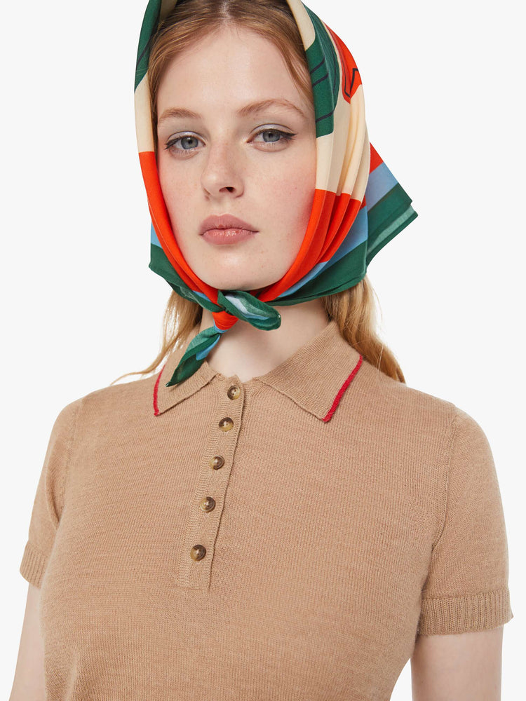 Close up view of a woman in a light khaki with red details and trim knit polo shirt with short sleeves, a buttoned V-neck, ribbed hems and a slightly cropped fit.