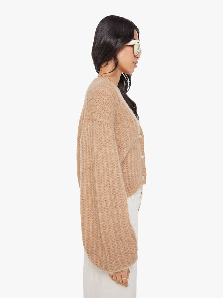 Side  view of a woman in a light khaki  V-neck cardigan with drop shoulders, oversized balloon sleeves, ribbed hems and a cropped fit. 