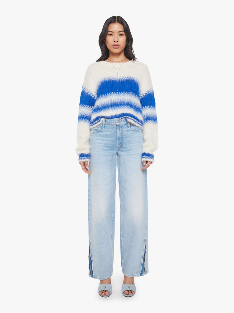 Full body view of a woman in an off-white with blue stripes crewneck sweater with drop shoulders, thick ribbed hems and a slightly cropped fit. 