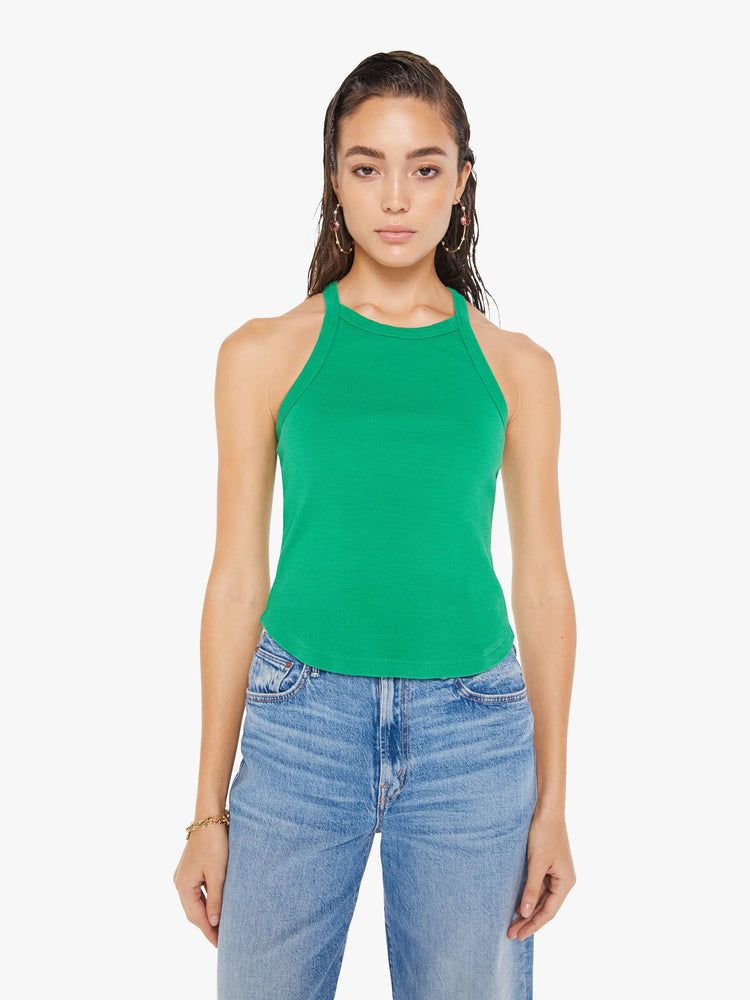 Front view of a woman wearing a green ribbed tank top with a cropped curved hem, paired with a medium blue wash jean.