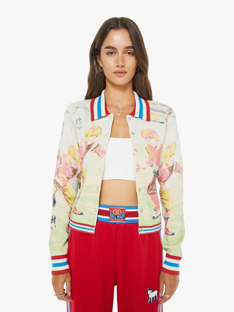 Front view of a woman in a button up sweater with a faded sports graphic inspired by a children's book drawing and red, white and blue striped trim.