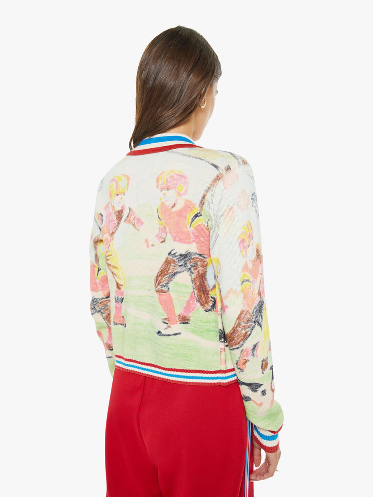 Back view of a woman in a button up sweater with a faded sports graphic inspired by a children's book drawing and red, white and blue striped trim.
