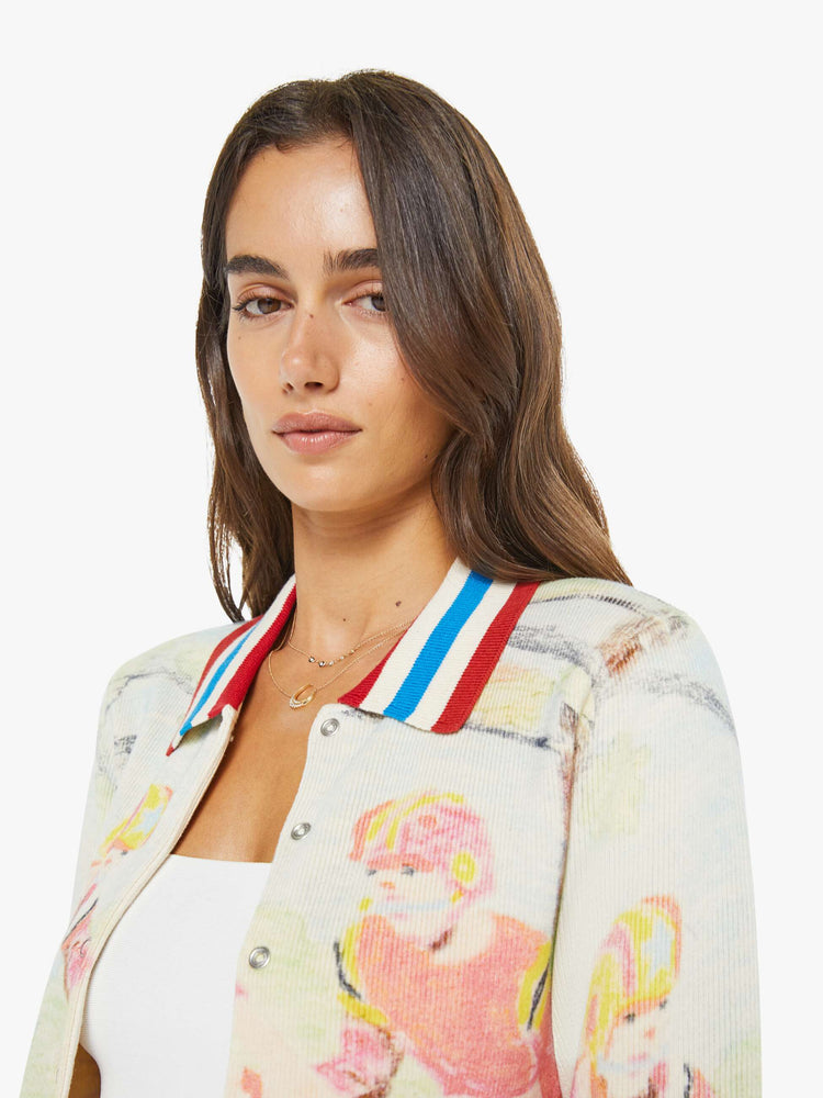 Close up view of a woman in a button up sweater with a faded sports graphic inspired by a children's book drawing and red, white and blue striped trim.