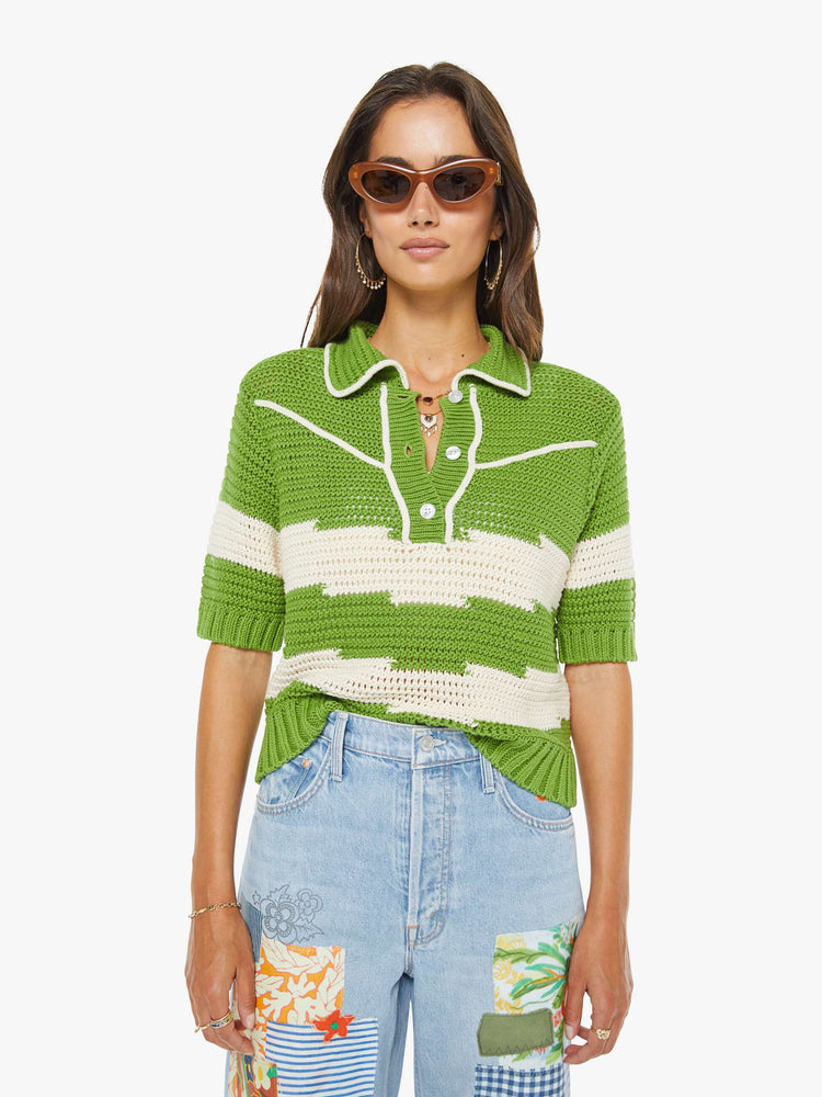 Front view of a woman in a green and off white stripes collared knit top with short sleeves, a buttoned V-neck, ribbed hems and a loose fit.