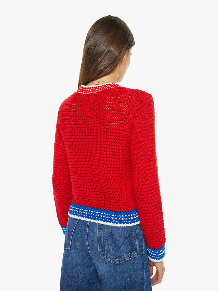 Back view of a woman in a bright red with blue and white trim and a martini glass in white on the front sweater with long sleeves and a cropped fit. 