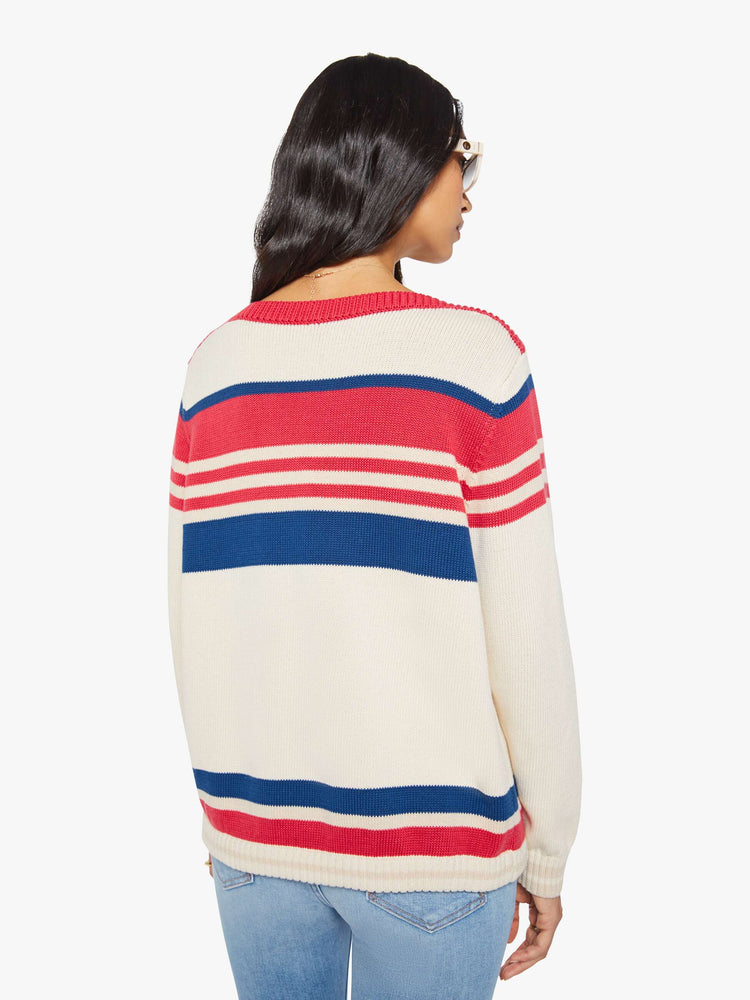 Back view of a woman in off-white with red and blue horizontal stripes long-sleeve sweater with a boat neck, drop shoulders, ribbed hems, a drawstring waist and an oversized fit.
