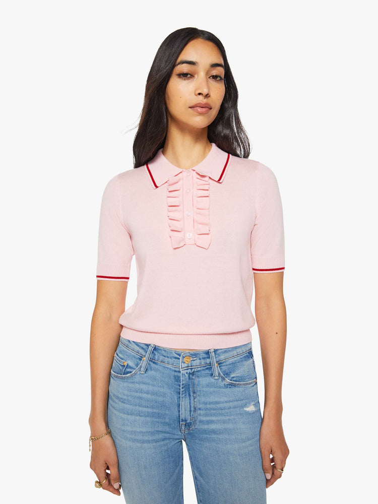 Front view of a woman in a light pink and red short sleeve polo with a buttoned V-neck, ruffle details, ribbed hems and a slightly cropped fit.