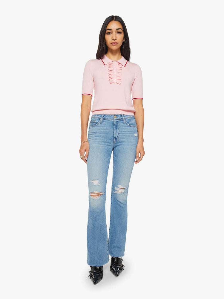 Full body view of a woman in a light pink and red short sleeve polo with a buttoned V-neck, ruffle details, ribbed hems and a slightly cropped fit.