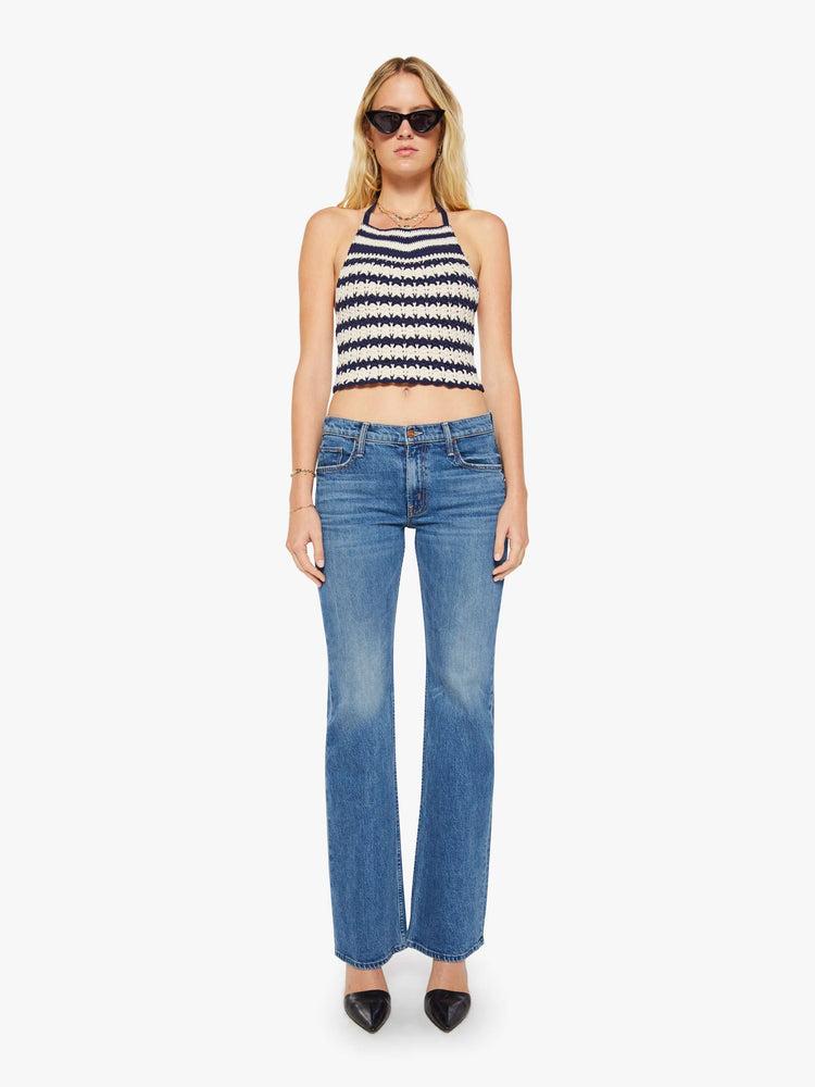 Full body view of a woman in a navy and off white stripes knit halter top with thin straps and a cropped, narrow fit.
