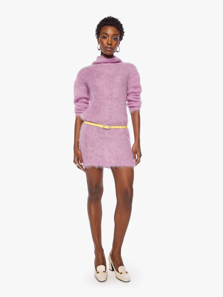 Full body view of a woman in a light lavender mini dress with a soft turtleneck, long sleeves, an open back and a thigh-grazing hem.