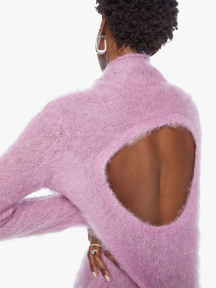 Back close up view of a woman in a light lavender mini dress with a soft turtleneck, long sleeves, an open back and a thigh-grazing hem.