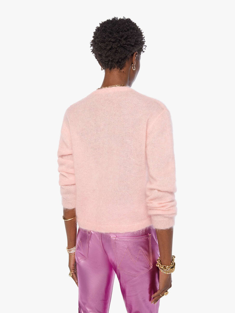 Back view of a woman in a soft baby pink crewneck, ribbed hems and a cropped fit.