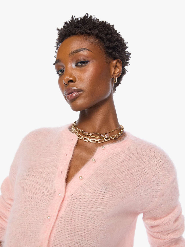 Close up view of a woman in a soft baby pink crewneck, ribbed hems and a cropped fit.