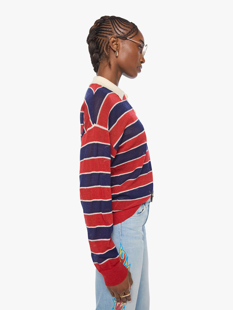 Side view of a woman in a red and navy stripes with a cream collar and button placket rugby polo with this long-sleeve top featuring drop shoulders and an oversized fit.