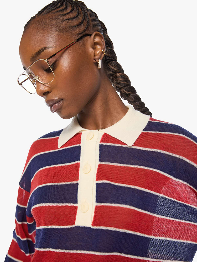 Close up view of a woman in a red and navy stripes with a cream collar and button placket rugby polo with this long-sleeve top featuring drop shoulders and an oversized fit.