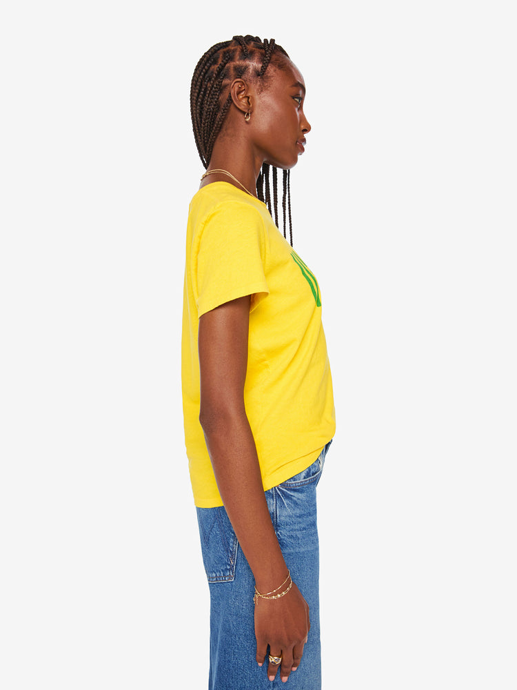 Side view of a woman bright yellow tee features a pink and green text graphic on the front.