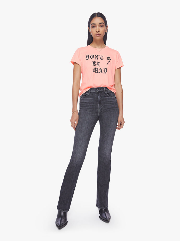Full body view of a woman slightly sheer crewneck baby pink tee features black graphic text and a rose on the front.
