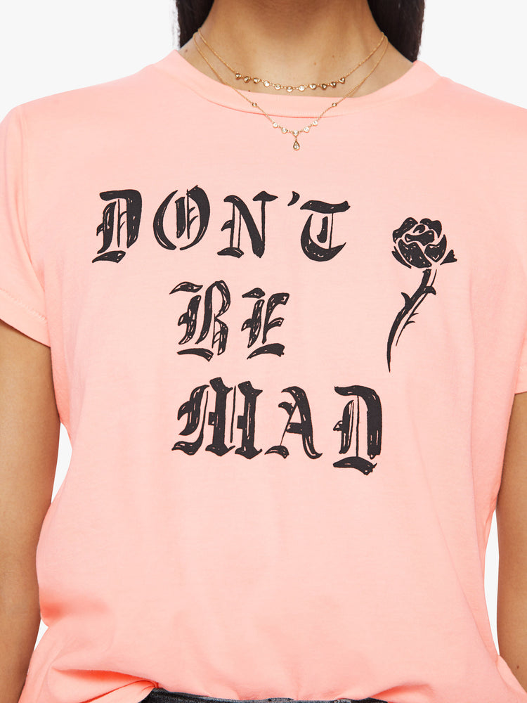 Close up view of a woman slightly sheer crewneck baby pink tee features black graphic text and a rose on the front.