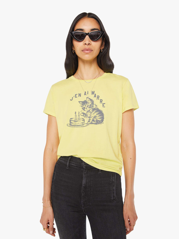 Front view of a woman in a pale yellow tee features a kitten graphic and text in French on the front.