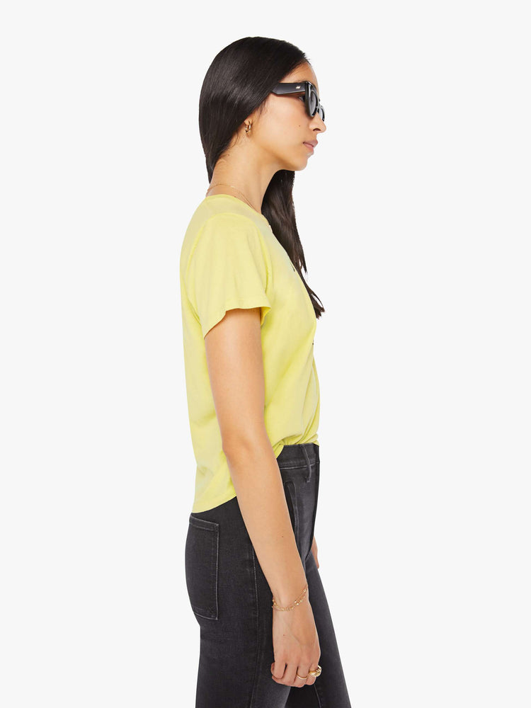 Side view of a woman in a pale yellow tee features a kitten graphic and text in French on the front.
