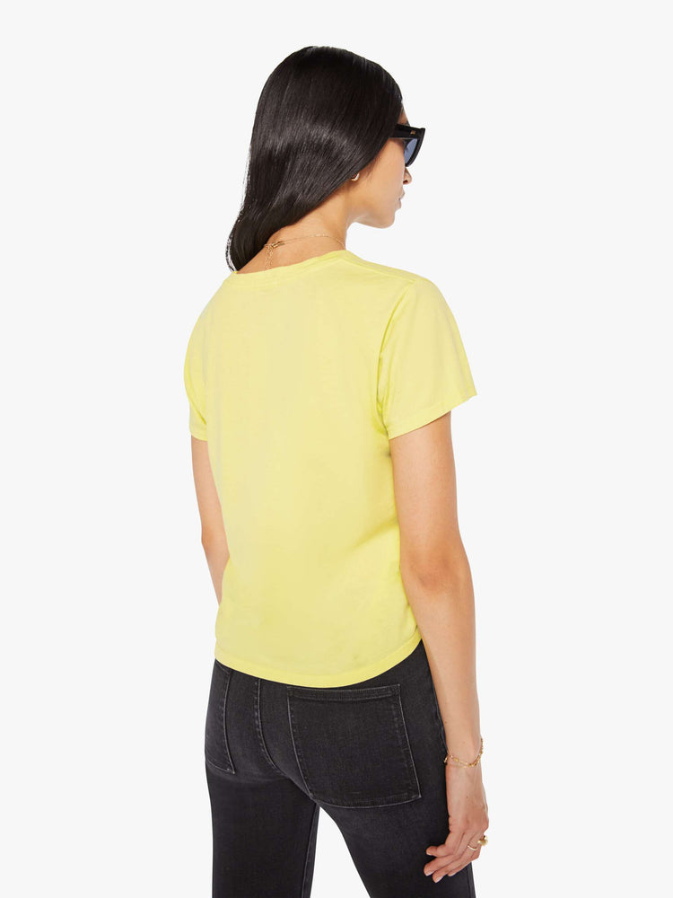 Back view of a woman in a pale yellow tee features a kitten graphic and text in French on the front.