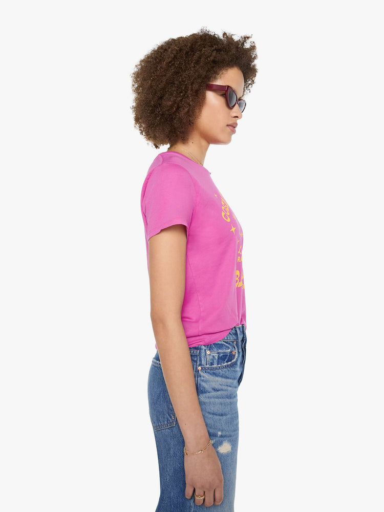 Side view of a woman in a bright pink tee with a celestial saloon graphic in yellow across the chest.