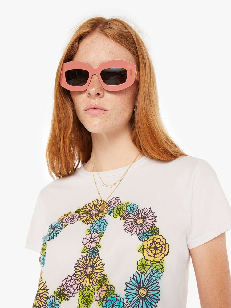 Front close up view of a white crew neck tee featuring a peace sign made of flowers.