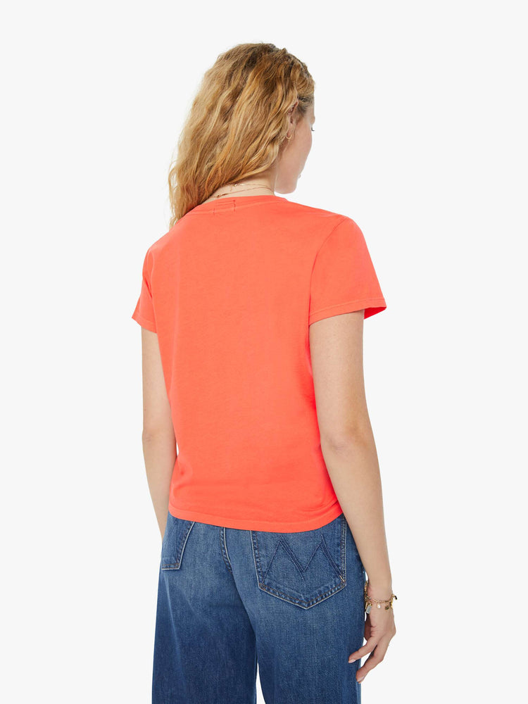 Back view of a woman in a slightly sheer orange crewneck with a slim fit featuring a text graphic "Spritz" in yellow styled with blue jeans.