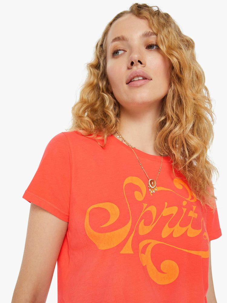Detailed view of a woman in a slightly sheer orange crewneck with a slim fit featuring a text graphic "Spritz" in yellow.