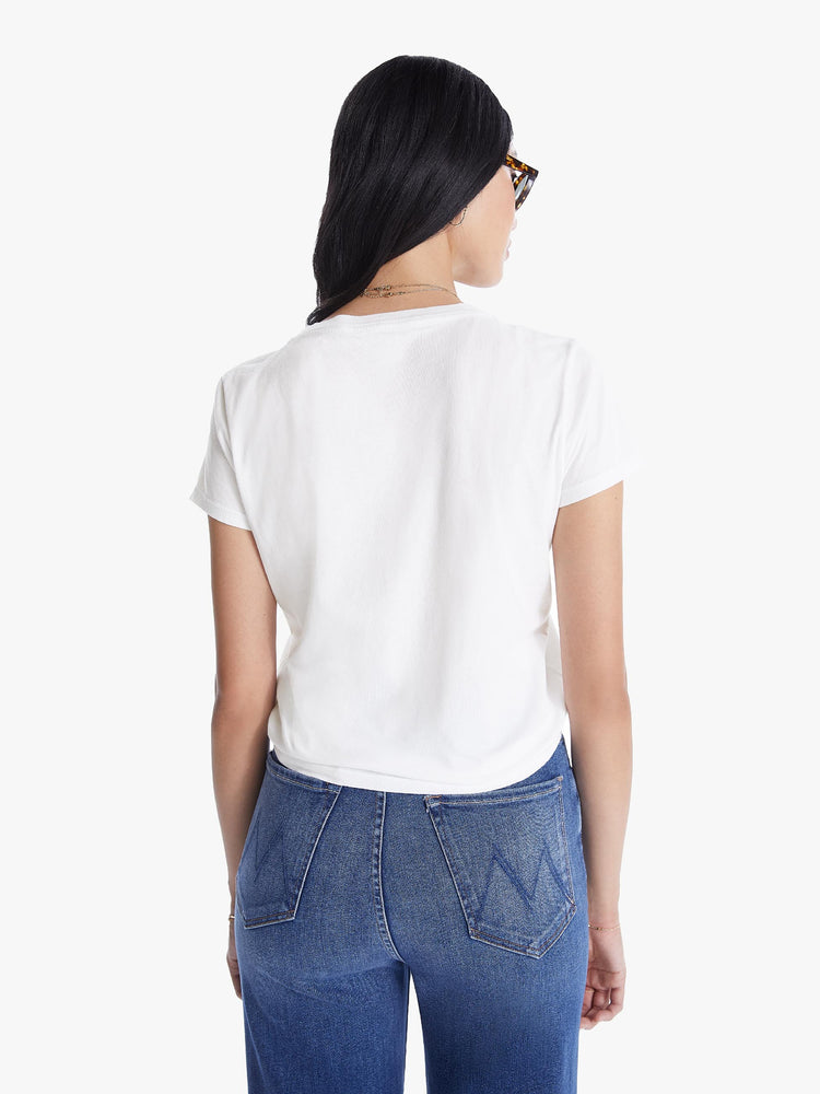 A back view of a woman wearing a fitted white crew neck tee, paired with a medium blue wash jean.