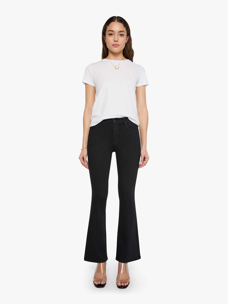 Full body view of a woman wearing a fitted white crew neck tee, paired with a black wash jean.