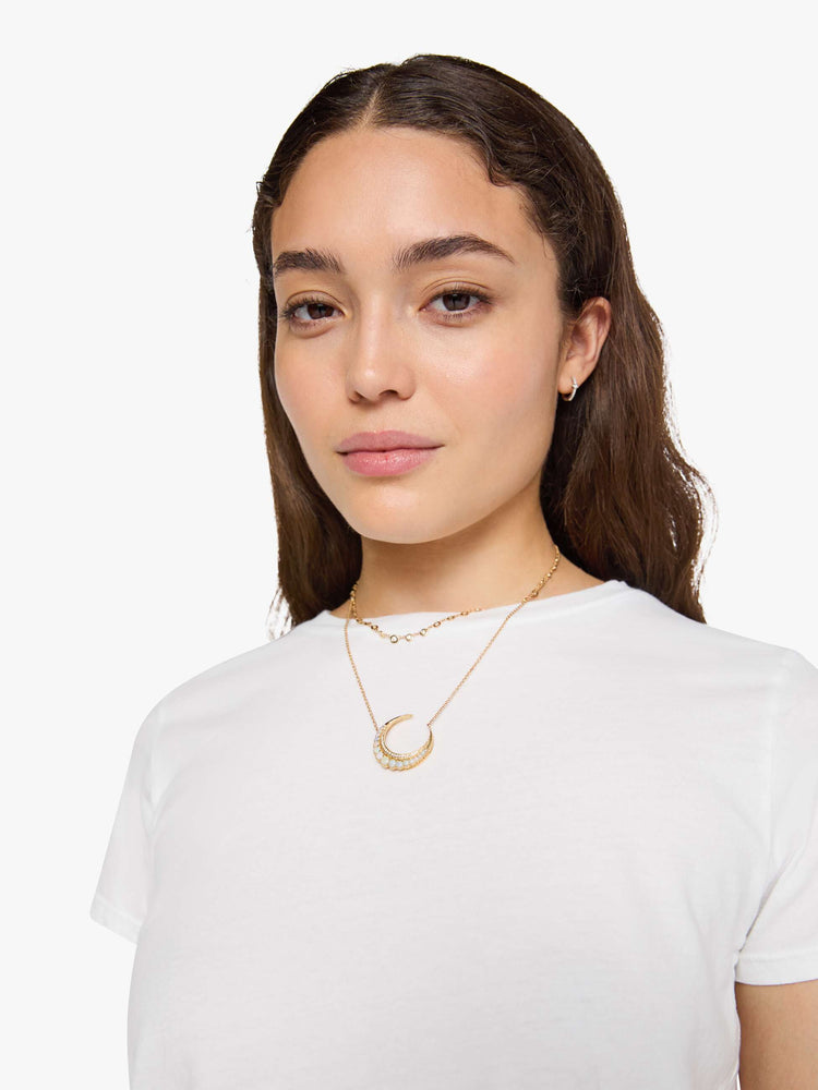 Close up view of a woman wearing a fitted white crew neck tee, paired with a black wash jean.