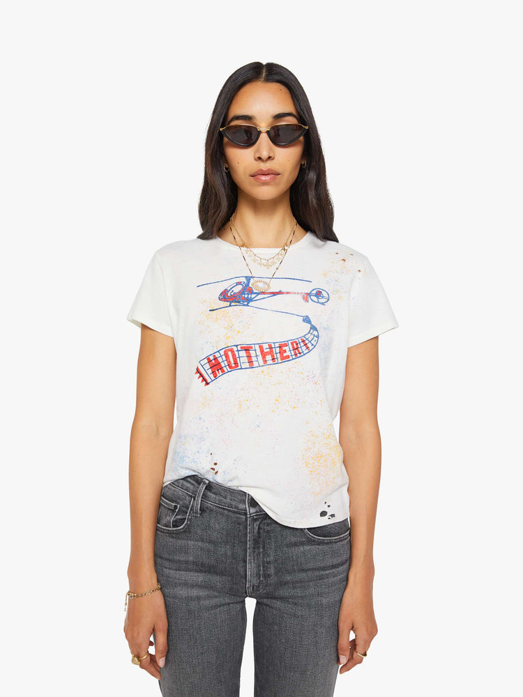 Front view of a woman in off-white tee features a blue and red vintage-inspired helicopter graphic and MOTHER's name on the front, colorful paint splatters and distressed details throughout.