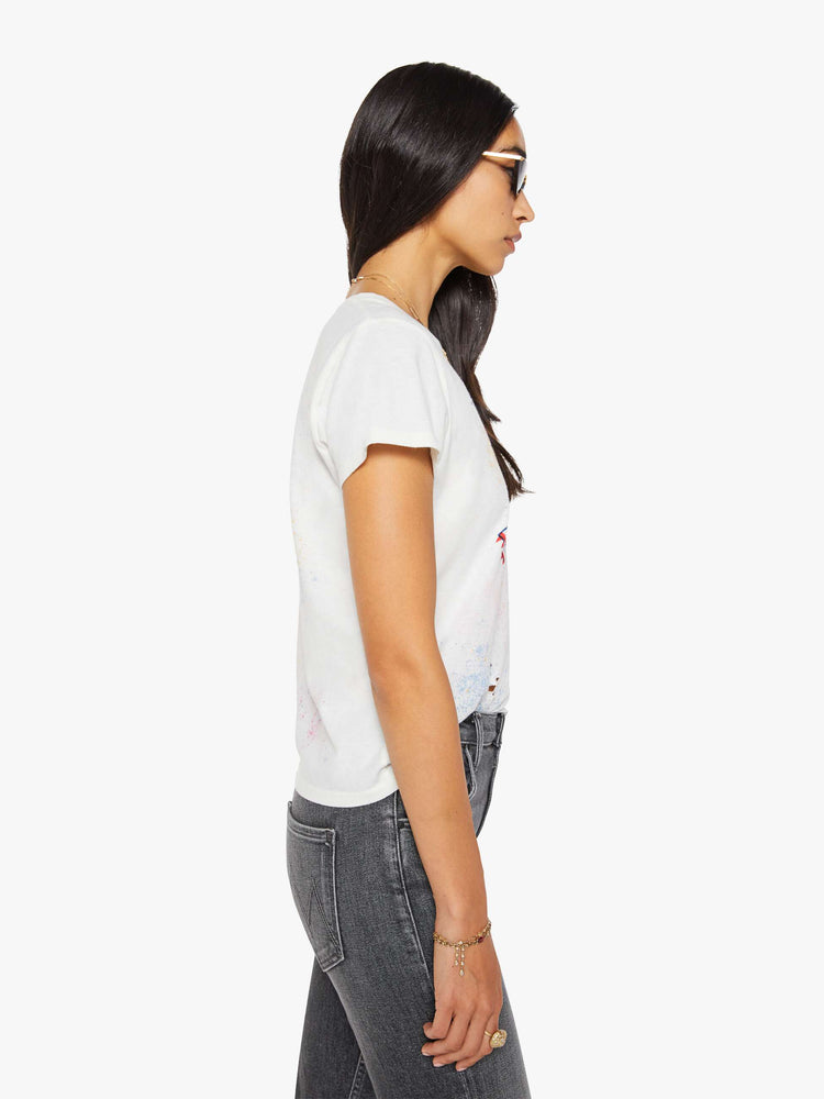 Side view of a woman in off-white tee features a blue and red vintage-inspired helicopter graphic and MOTHER's name on the front, colorful paint splatters and distressed details throughout.