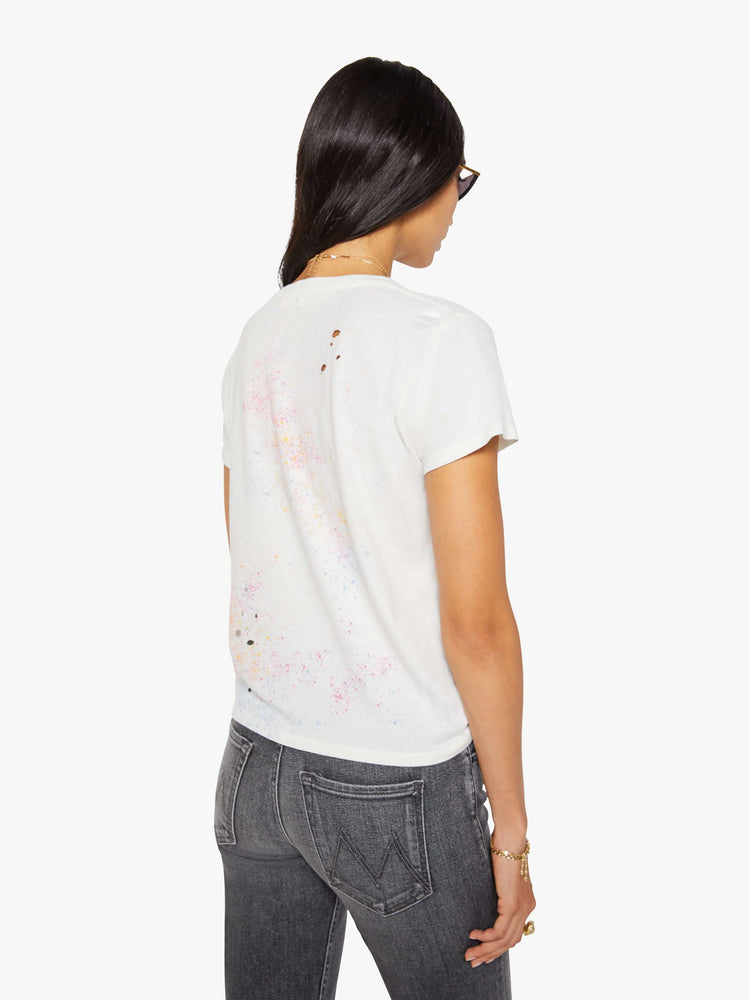 Back view of a woman in off-white tee features a blue and red vintage-inspired helicopter graphic and MOTHER's name on the front, colorful paint splatters and distressed details throughout.