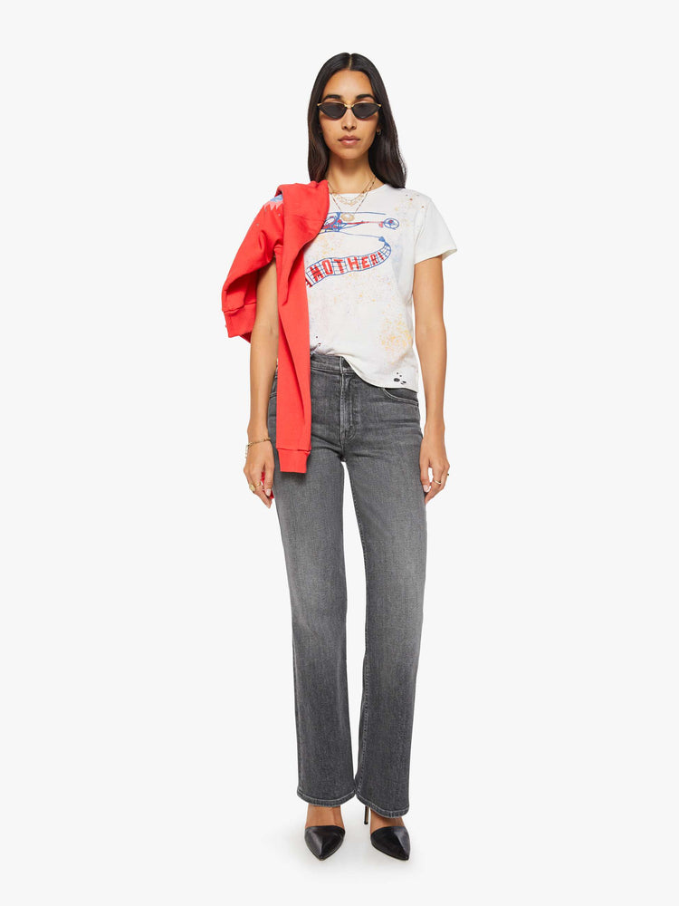 Full body view of a woman in off-white tee features a blue and red vintage-inspired helicopter graphic and MOTHER's name on the front, colorful paint splatters and distressed details throughout.
