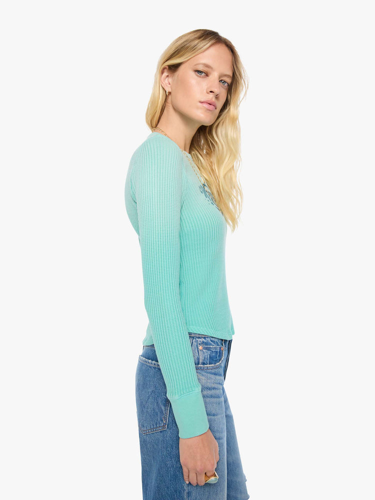 Side view of a woman in long sleeve shirt sun-faded turquoise with a vintage-inspired Western graphic across the chest.