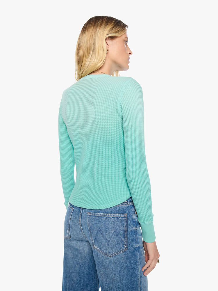 Back view of a woman in long sleeve shirt sun-faded turquoise with a vintage-inspired Western graphic across the chest.