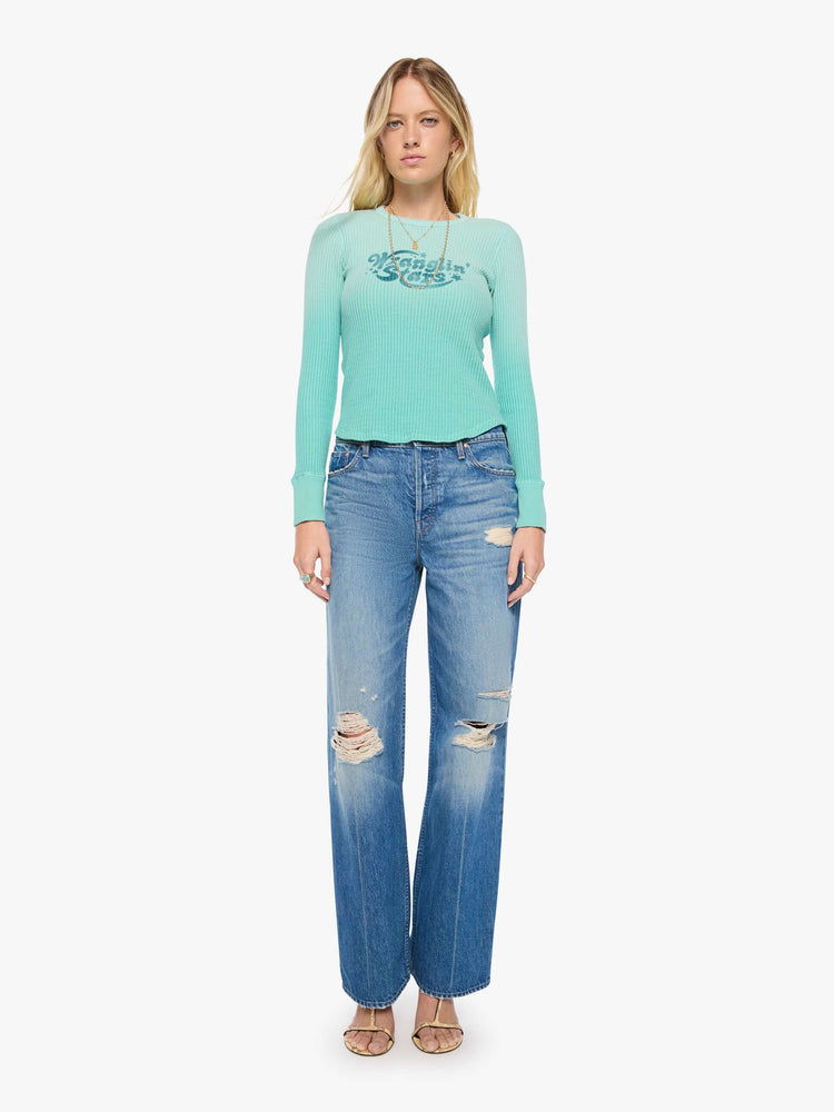 Full body view of a woman in long sleeve shirt sun-faded turquoise with a vintage-inspired Western graphic across the chest.